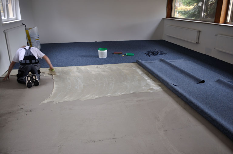 Kugelgarn Verlegung, Bodenleger trägt Klebstof auf