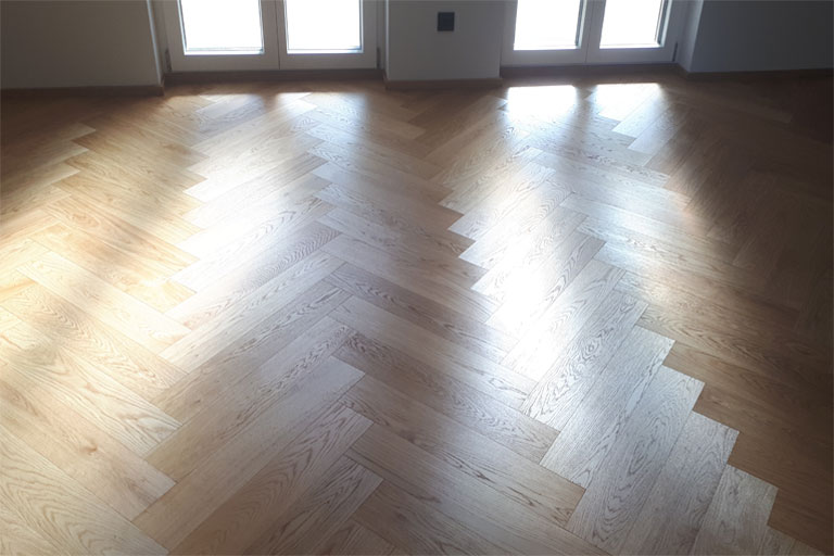 Nahaufnahme eines Parkettbodens im Fischgrätmuster